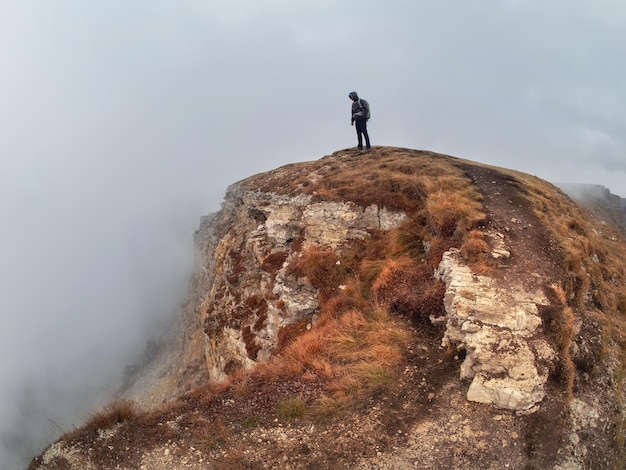 Silhouette uomo al di sopra di una nebbiosa nuvole mattutina paesaggio collinare Alone Rock con viaggiatore uomo sopra le nuvole nella nebbiosa mattina nel Caucaso