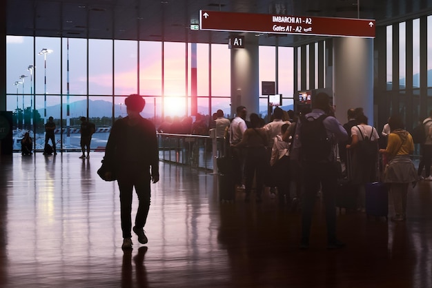 silhouette uomo al gate d'imbarco dell'aeroporto al tramonto controluce