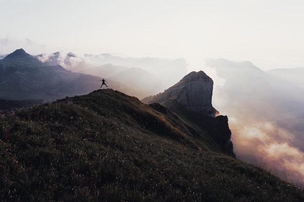 Silhouette uomo che salta sopra la montagna contro il cielo