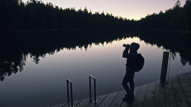 Silhouette viaggiatore fotografare vista panoramica nella foresta fiume Molo di legno Una donna che spara bella notte magica oscura Look Ragazza scattare foto sulla fotocamera