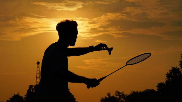 Silhouettes Man tiene il volano e la racchetta da badminton