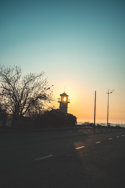 Silhoutette light house con tramonto tropicale Faro proiettore fascio attraverso l'aria di mare di notte