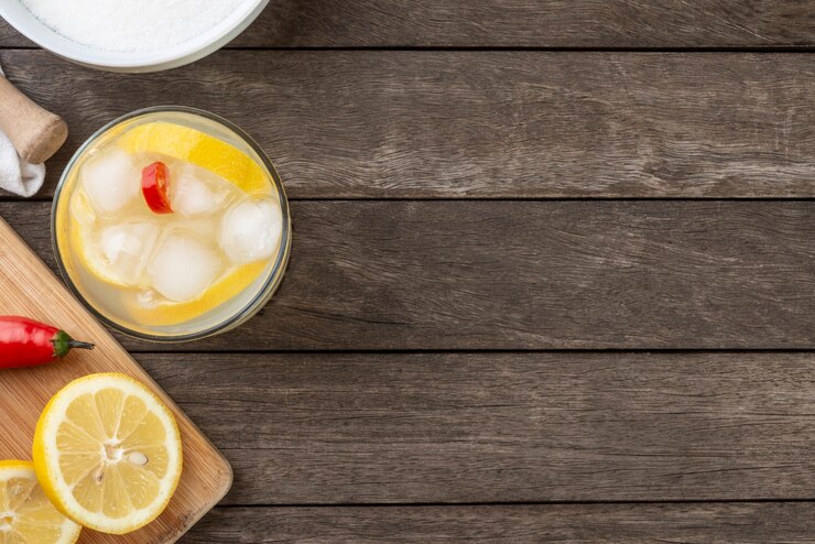 Silician brasiliano limone e peperoncino rosso caipirinha in un bicchiere con ghiaccio con fette di frutta su tavola di legno con spazio di copia