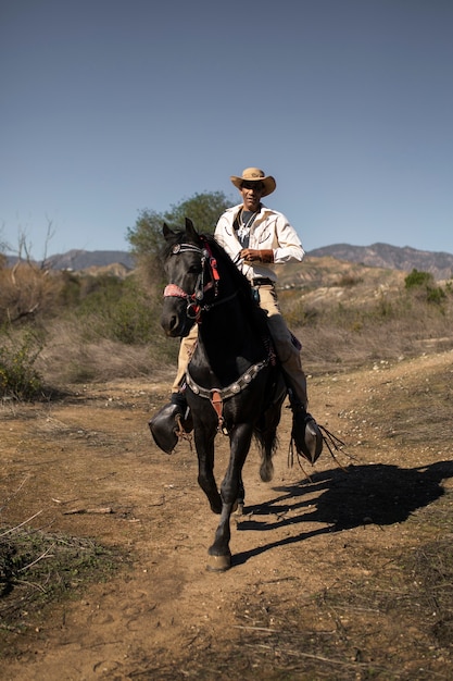 Siluetta del cowboy con il cavallo contro la luce calda