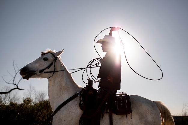 Siluetta del cowboy con il cavallo contro la luce calda