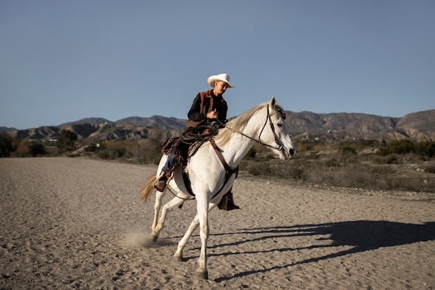 Siluetta del cowboy con il cavallo contro la luce calda