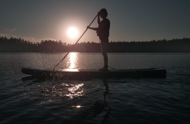 Siluetta del surfista SUP Ricreazione attiva sull'acqua