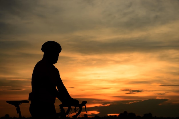 Siluetta dell'uomo asiatico giro in bicicletta sul tramonto