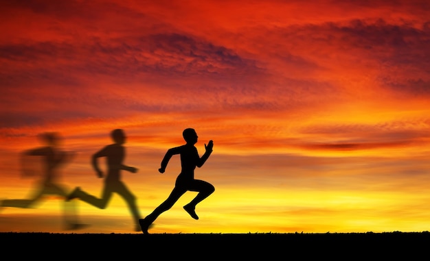 Siluetta dell'uomo che corre contro il cielo colorato. Sagoma di uomo che corre su sfondo infuocato al tramonto