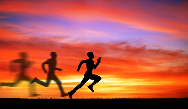 Siluetta dell'uomo che corre contro il cielo colorato. Sagoma di uomo che corre su sfondo infuocato al tramonto