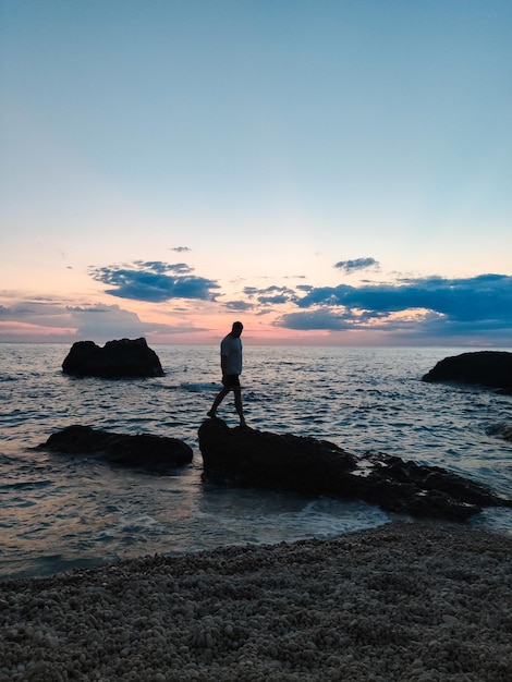 Siluetta dell'uomo che gode della vista del tramonto sopra il mare