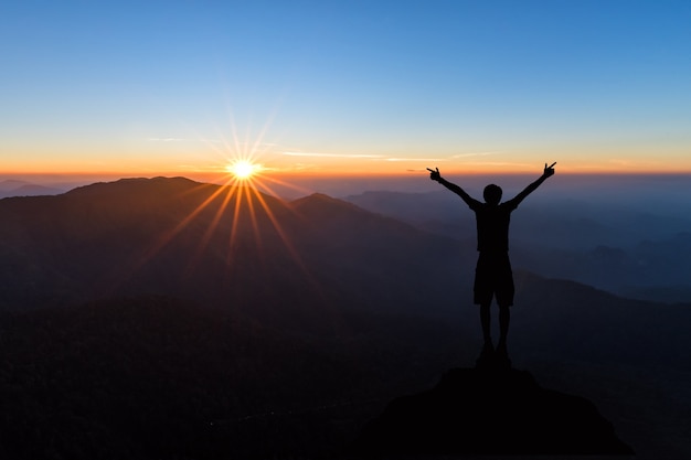 Siluetta dell&#39;uomo che spande mano e gode dell&#39;alba fantastica