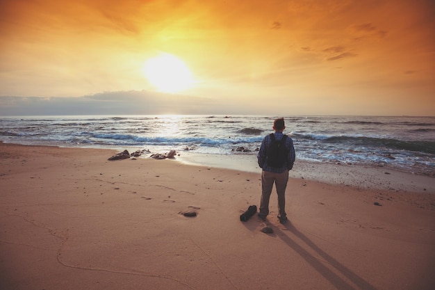 Siluetta dell'uomo sulla spiaggia che guarda il tramonto magico