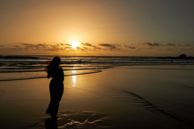 Siluetta della donna che guarda il tramonto sulla spiaggia.