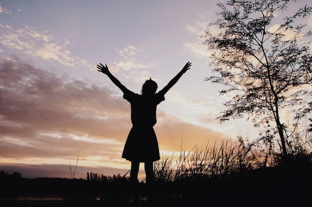 Siluetta della donna felice con il cielo di tramonto