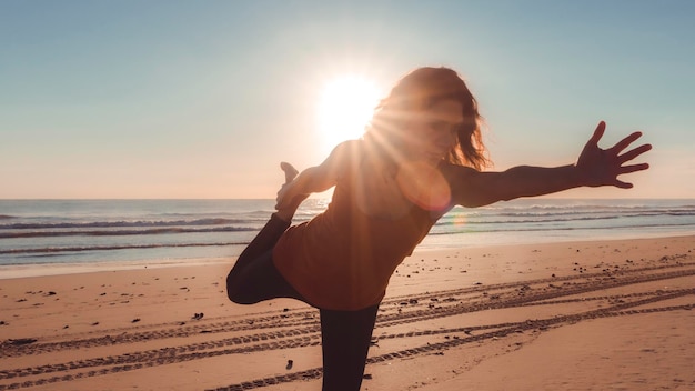 Siluetta della donna nella posa di yoga sulla spiaggia