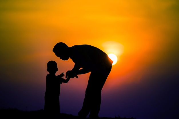 Siluetta della famiglia che il padre sta giocando con il ragazzo felicemente con il cielo al tramonto