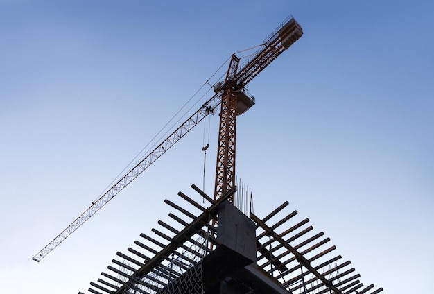 Siluetta della gru a torre di costruzione con lo sfondo del tramonto alla sera