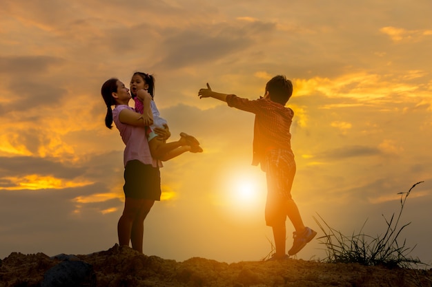 Siluetta della madre e del bambino che giocano ai precedenti di tramonto del campo