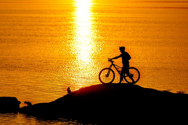 Siluetta dello sportivo che guida una bicicletta sulla spiaggia