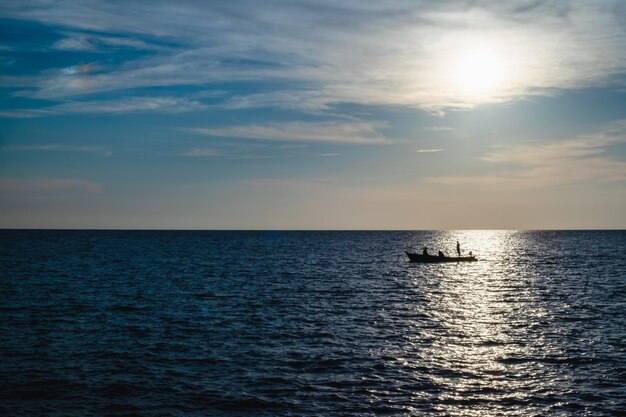 Siluetta di un pescatore sulla barca da pesca con il mare e il cielo blu