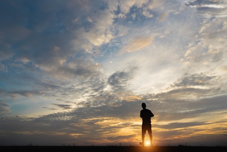 Siluetta di un uomo felice che cammina al tramonto.
