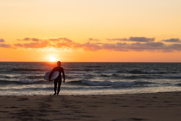 Siluetta di un uomo in muta che cammina in avanti al tramonto luminoso