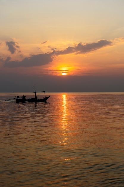 Siluetta di un uomo su una barca durante il tramonto in acqua di mare. Tailandia