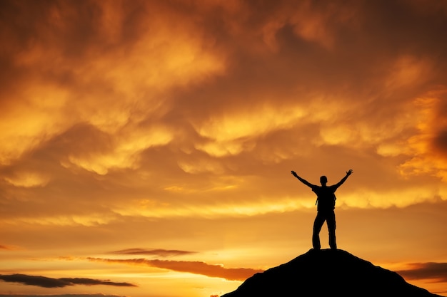 Siluetta di un uomo sulla cima di una montagna contro il cielo al tramonto. Sport e concetto di vita attiva