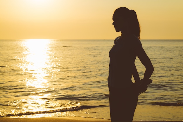 Siluetta di una donna snella sulla spiaggia durante l&#39;esercizio mattutino.