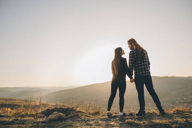 Siluetta di una femmina e di un maschio che si tengono per mano al tramonto