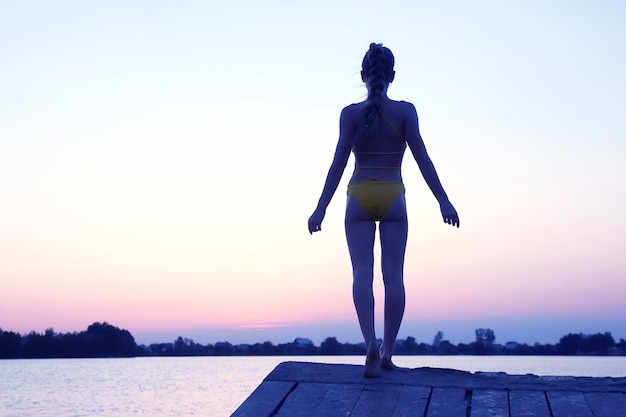 Siluetta di una ragazza con un tramonto sull'acqua