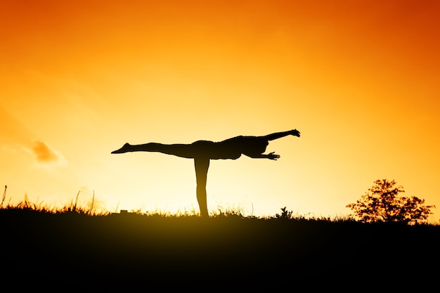 Siluetta di uno yogi al tramonto. Esercizi per l'equilibrio.