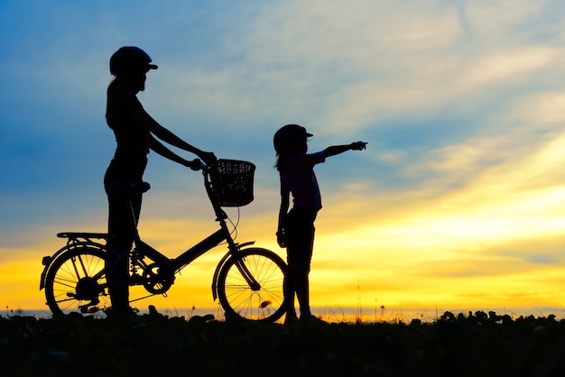 Siluette della famiglia di motociclisti sulla spiaggia al tramonto bellissimo.