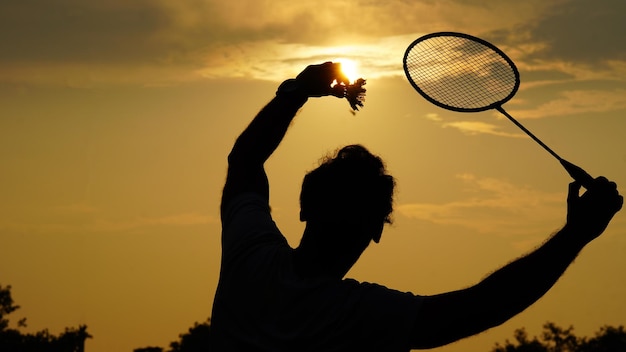 Siluette l'uomo che gioca a badminton con una navetta in mano