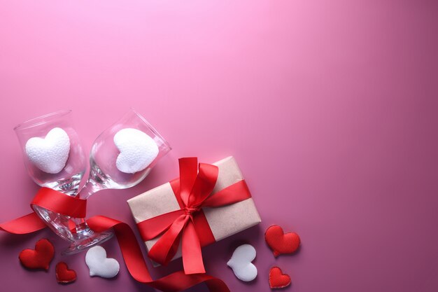 Simboli di amore della cartolina d'auguri del fondo di San Valentino, decorazione rossa con i vetri su fondo rosa. Vista dall'alto con spazio di copia e testo. Superficie piana