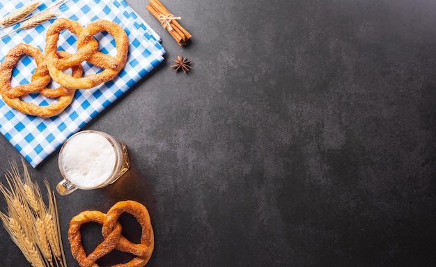 Simboli di decorazione del festival dell'Oktoberfest realizzati con birra Pretzel e tessuto bavarese bianco e blu su sfondo di pietra scura