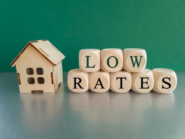 Simbolo dei tassi di casa bassi Parole concettuali 'tassi bassi' su cubi di legno vicino a case in miniatura