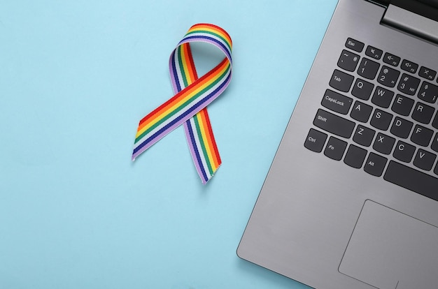 Simbolo del nastro dell'orgoglio del nastro arcobaleno per laptop e LGBT su sfondo blu Concetto di amore