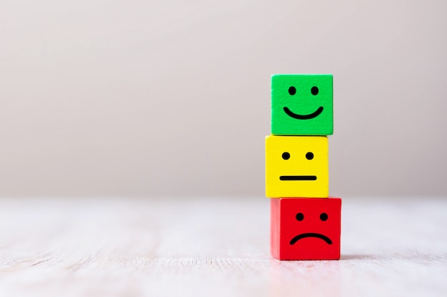 Simbolo del viso di emozione su blocchi cubo in legno. Valutazione del servizio, classificazione, recensione dei clienti, concetto di soddisfazione e feedback.