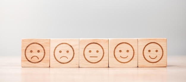 Simbolo del viso emotivo su blocchi di legno Classificazione della valutazione del servizio Valutazione della soddisfazione della recensione del cliente e concetto di feedback