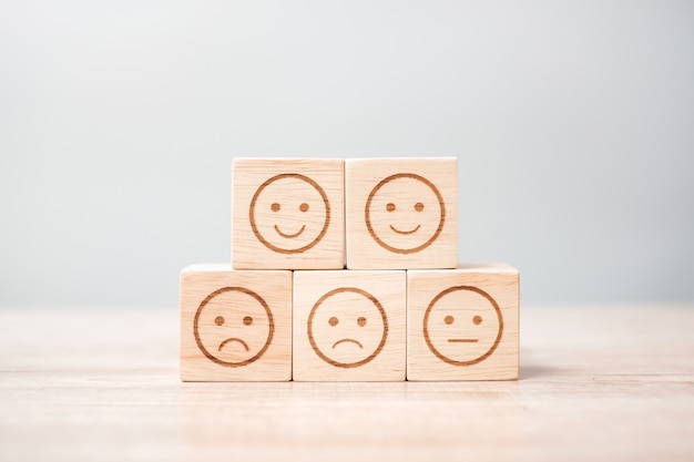 Simbolo del viso emozione su blocchi di legno. Valutazione del servizio, classifica, recensione del cliente, soddisfazione, valutazione e concetto di feedback