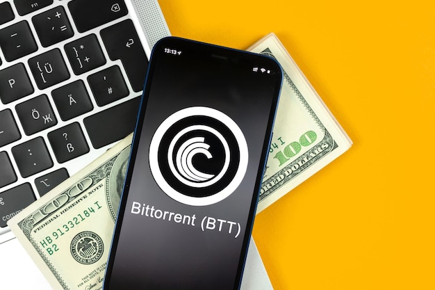 Simbolo della moneta BTT Bittorrent. Fai trading con criptovaluta, denaro digitale e virtuale, operazioni bancarie con il concetto di telefono cellulare. Area di lavoro aziendale, tavolo con foto vista dall'alto del laptop