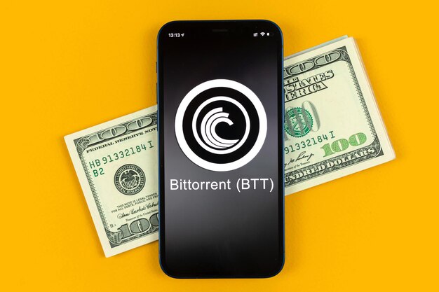 Simbolo della moneta BTT Bittorrent. Fai trading con criptovaluta, denaro digitale e virtuale, operazioni bancarie con il concetto di telefono cellulare. Area di lavoro aziendale, tavolo con foto vista dall'alto del laptop