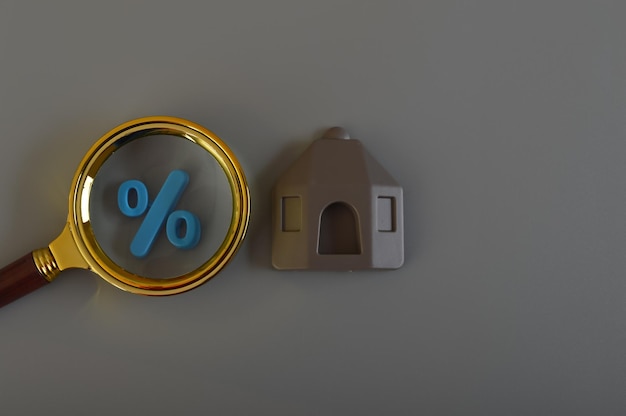 Simbolo di percentuale della lente d'ingrandimento e modello di casa Mutuo immobiliare e rischi