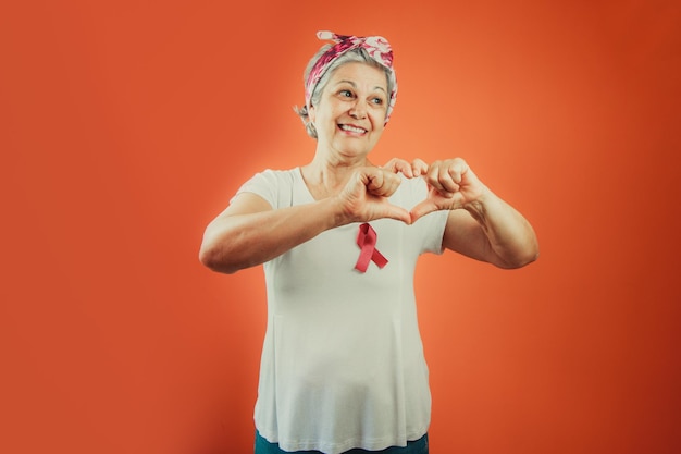 Simbolo di protezione del cancro al seno Donna matura con nastro rosa e maglietta bianca isolata per la campagna contro il cancro al seno