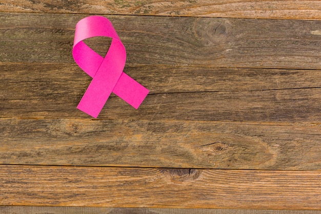 Simbolo di salute delle donne in nastro rosa sul bordo di legno.