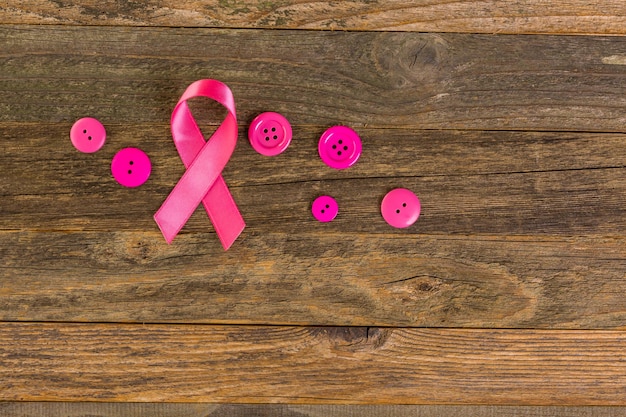 Simbolo di salute delle donne in nastro rosa sul bordo di legno.