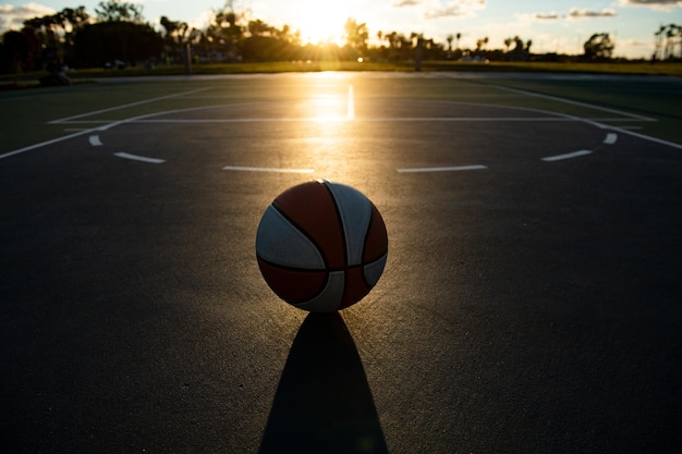 Simbolo di sport e fitness di pallacanestro di un'attività di svago di squadra che gioca sul tramonto. Copia spazio.