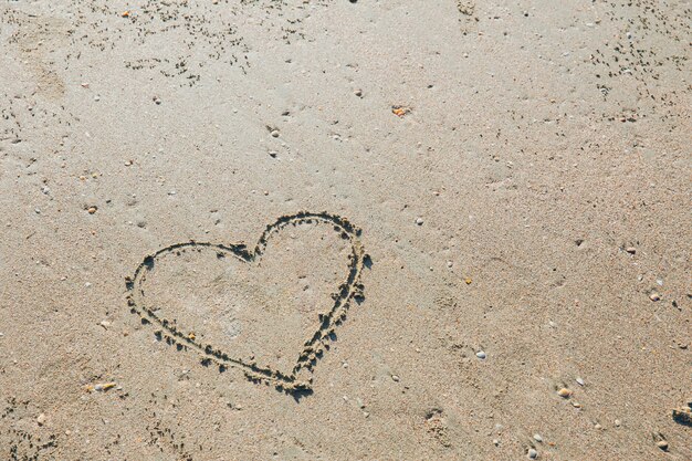 Simbolo disegnato a mano di amore del cuore sul concetto di estate di festa della sabbia della spiaggia del mare